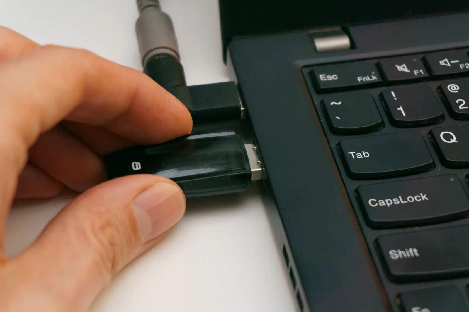 Hand inserting a USB drive into a laptop for local media export